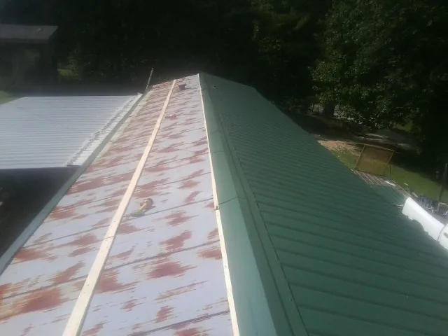 Old rusted panels beside newly installed green metal roofing — Wind Damage Roof Repair by Roofing Brothers in Campbellsport