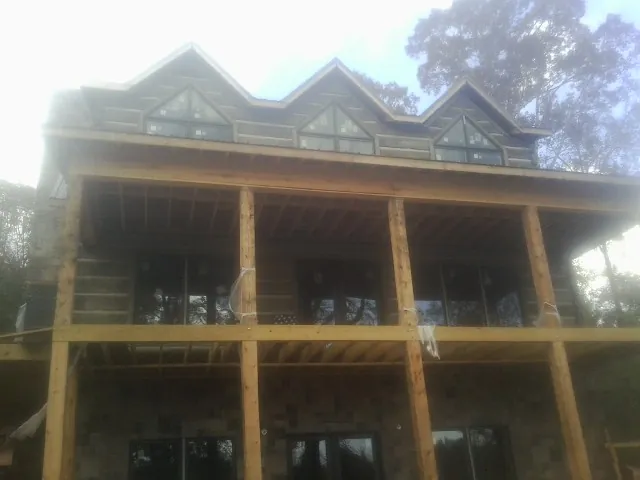 Dormers and porch framing on a large log home under construction — Roof Coating work by our crew in Campbellsport