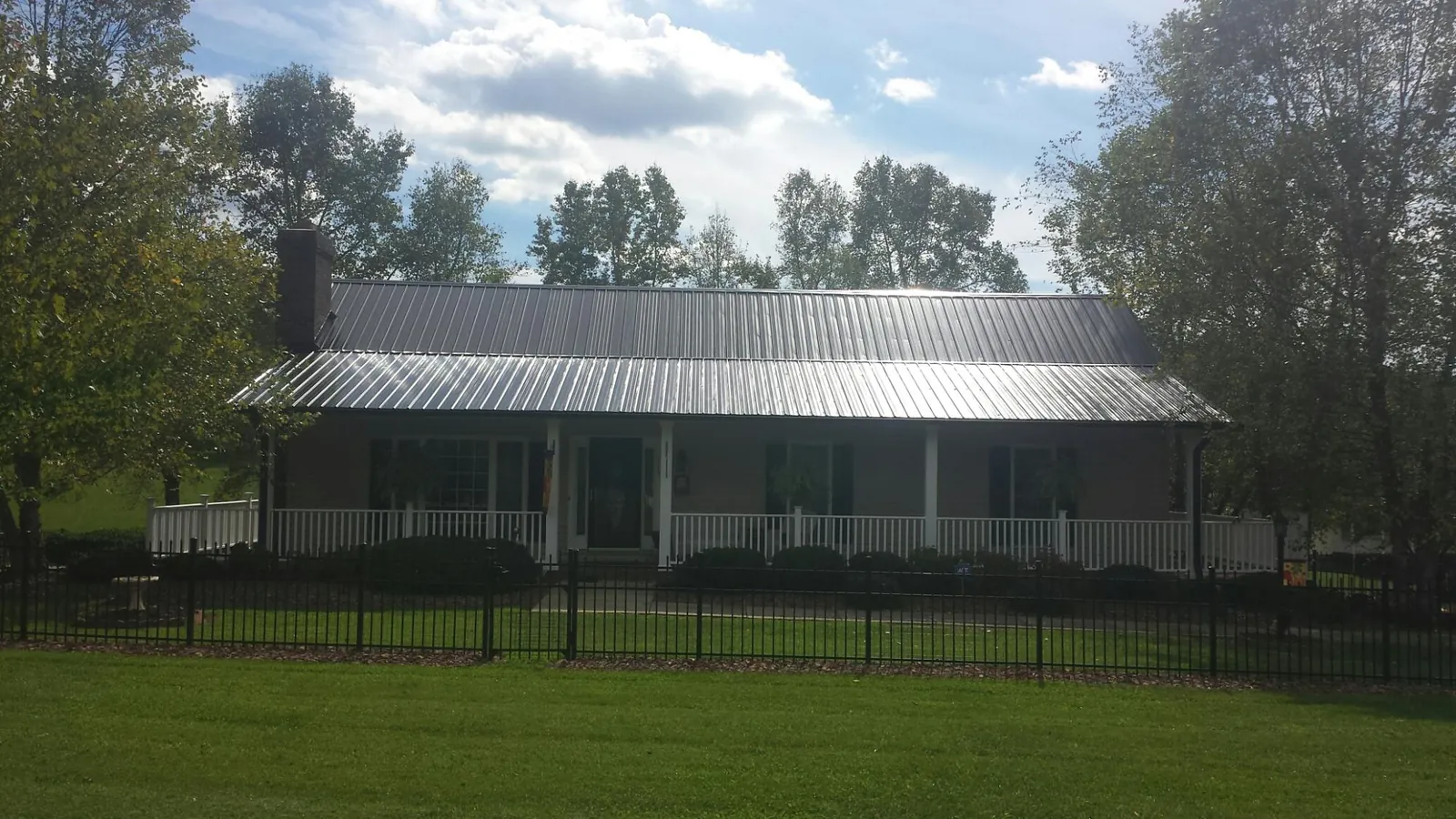 Gray metal roof on a brick ranch with a full width front porch — Gutter Guard Installation work by our crew in Campbellsport