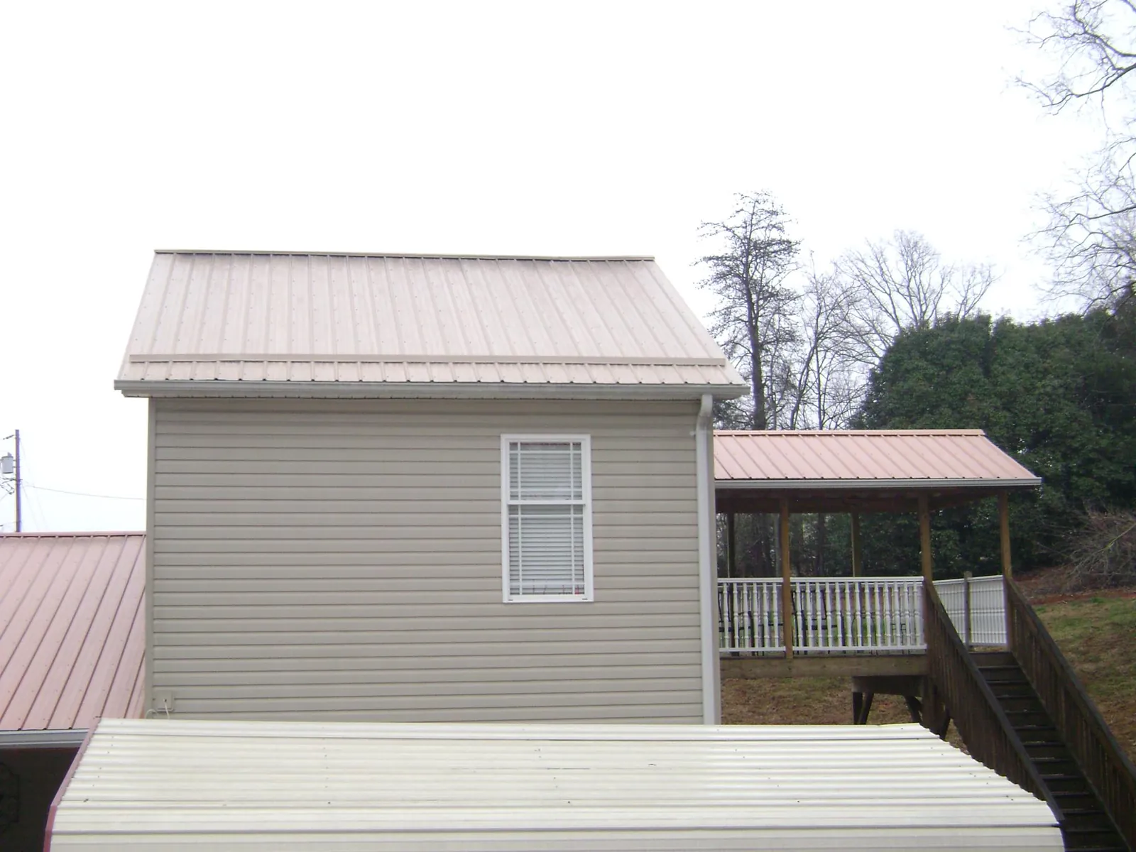 Tan metal roofs on a two story addition and attached porch, from a Roof Replacement job in Campbellsport
